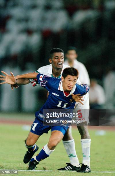 Footballer Kazuyoshi Miura of Japan is challenged by defender Hassan Mubarak, of the United Arab Emirates, in a qualifier for the 1998 FIFA World...