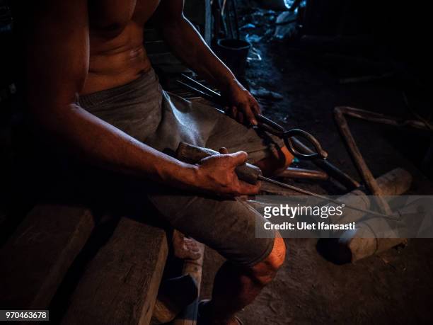 Worker holds a tool as they make traditional gong instruments at a workshop in Wirun village on June 7, 2018 in Sukoharjo, Central Java, Indonesia....