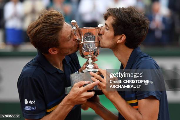 France's Pierre-Hugues Herbert and compatriot Nicolas Mahut kiss the trophy after winning the men's doubles final match against Austria's Oliver...
