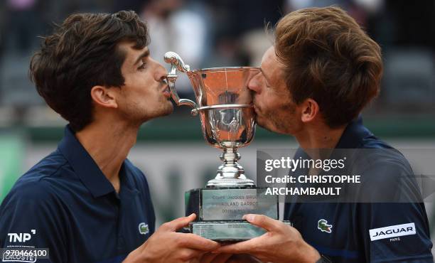 France's Pierre-Hugues Herbert and compatriot Nicolas Mahut kiss the trophy after winning the men's doubles final match against Austria's Oliver...