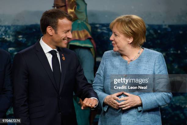 France's President Emmanuel Macron and Germany's Chancellor Angela Merkel discuss President Macron's suit ahead of the G7 Outreach Family photo, on...