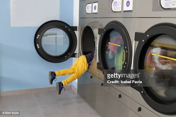 legs of boy in washing machine at laundromat - isabel pavia stock-fotos und bilder