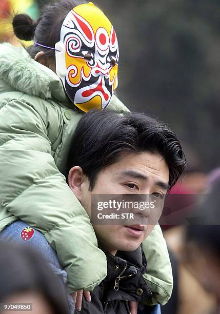 Young girl wears a mask as she arrives with her father at the Beijing West Railway station to catch their train back home after the Chinese Lunar New...