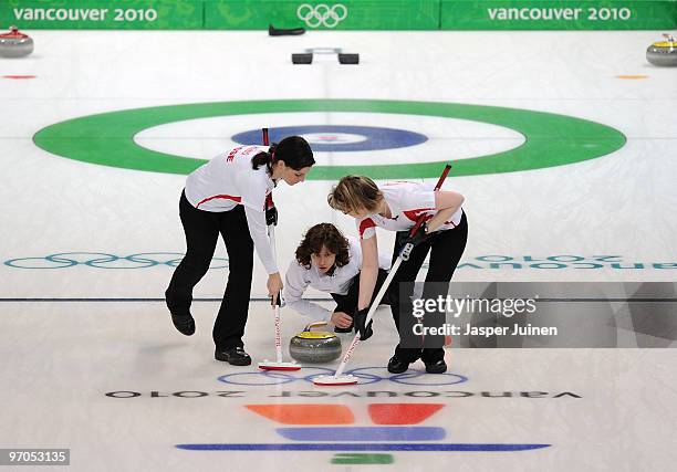 Skip Mirjam Ott of Switzerland releases the stone as teammates Carmen Kueng and Janine Greiner brush the ice during the women's curling semifinal...