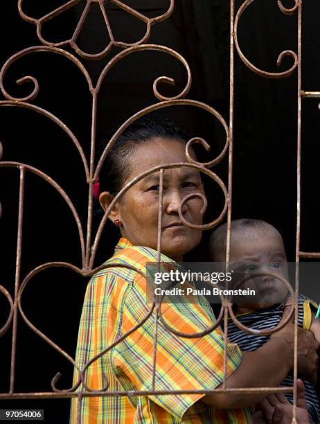Burmese migrant woman holds a baby looking out of the window of her apartment in a Burmese community where many work in the seafood industry February...