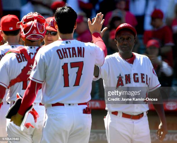 Shohei Ohtani gets a high five from coach Alfredo Griffin of the Los Angeles Angels of Anaheim after the game against the Texas Rangers at Angel...