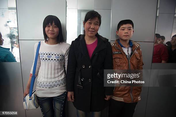 Migrant woman poses for a photo with her daughter and son before to enroll in the Shenzhen Quanshun Human Resources Co., Ltd, on February 23, 2010 in...