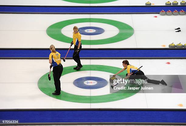 Anna Le Moine of Sweden releases the stone flanked by her teammates Eva Lund and and Cathrine Lindahl during the women's curling semifinal game...