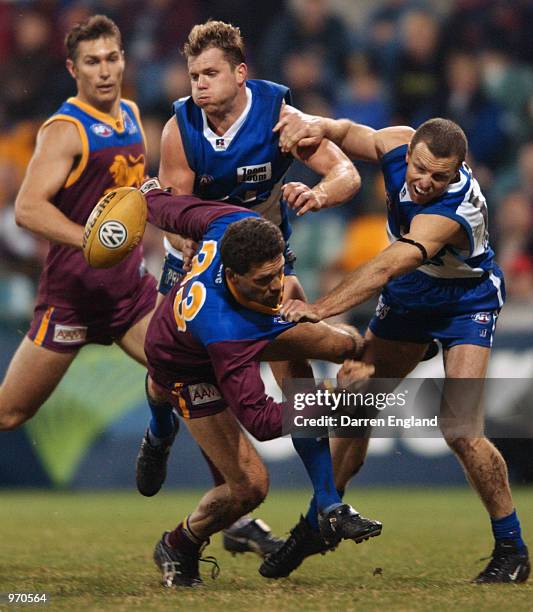 Darryl White of the Lions is tackled by Glenn Archer and John Blakey of the Kangaroos during the round 12 AFL match played between the Brisbane Lions...