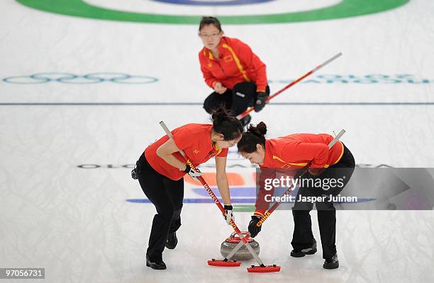 Qingshuang Yue and Yan Zhou brush the ice backdropped by skip Bingyu Wang during the women's curling semifinal game between Sweden and China on day...