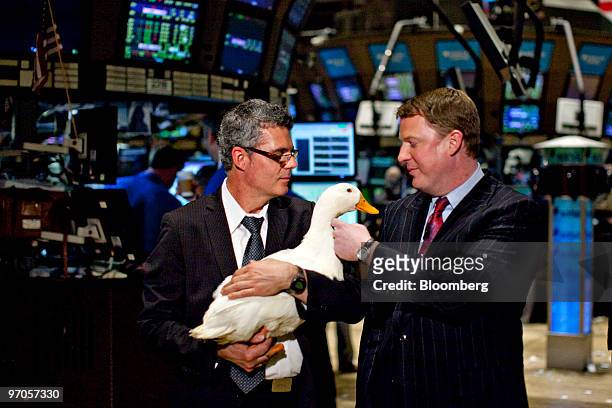 Paul Amos, president and chief operating officer of Aflac Inc., right, pets the Aflac Duck as its held by Todd Evans, animal handler with Dawn Animal...