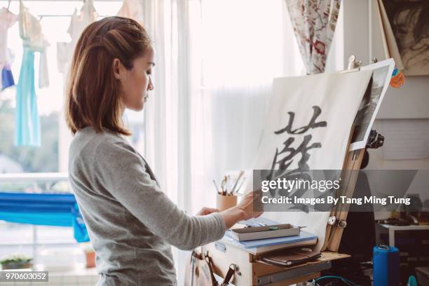 pretty young lady practicing chinese calligraphy at home. - chinesisches schriftzeichen stock-fotos und bilder