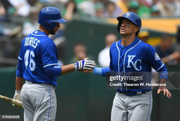 Ryan Goins of the Kansas City Royals is congratulated by Ramon Torres after Goins scored against the Oakland Athletics in the top of the second...