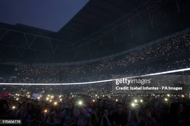 Fans in the crowd hold up their mobiles with the torches turned on during Capital's Summertime Ball with Vodafone at Wembley Stadium, London. PRESS...