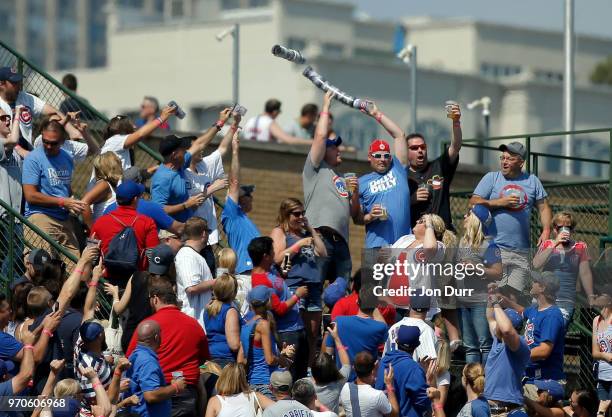 Fan tips over an stack of empty beer cups as some fall onto Waveland Avenue while other fans in the bleachers pass empty beer cups to stack them...