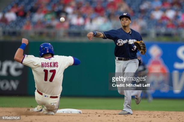 Orlando Arcia of the Milwaukee Brewers turns a double play against Rhys Hoskins of the Philadelphia Phillies in the bottom of the eighth inning at...