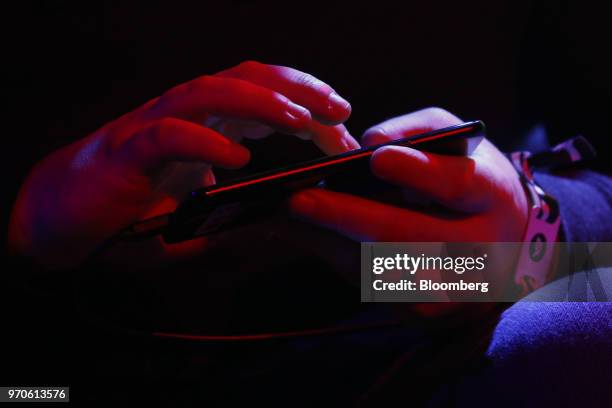 An attendee holds a mobile device while playing a video game during an Electronic Arts Inc. Event ahead of the E3 Electronic Entertainment Expo in...