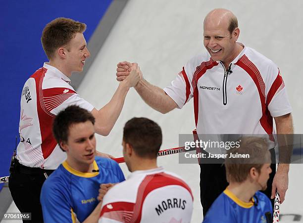 Skip Kevin Martin of Canada celebrates with his teammate Marc Kennedy at the end of the men's curling semifinal game between Canada and Sweden on day...