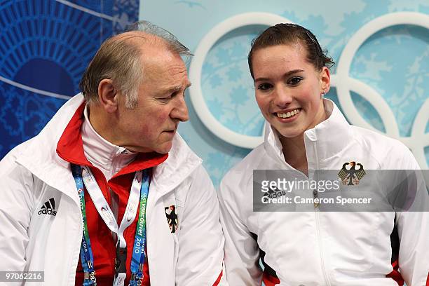 Sarah Hecken of Germany sits in the kiss and cry area with trainer Peter Sczypa after her skate in the Ladies Free Skating on day 14 of the 2010...