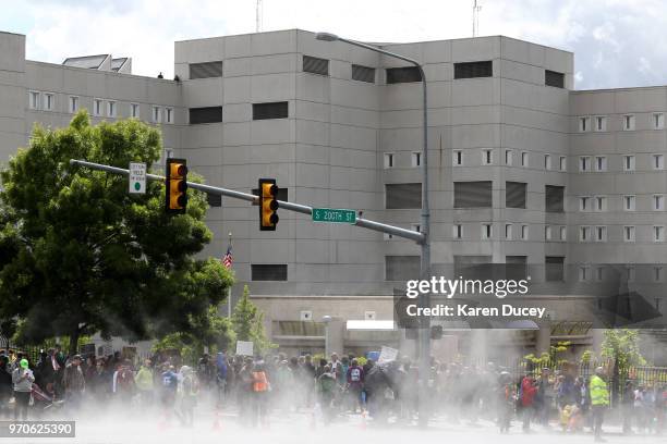 Steam rises off the street after a rainstorm drenched protesters outside a Federal Detention Center holding migrant women on June 9, 2018 in SeaTac,...