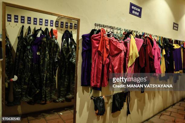 This picture taken on May 15, 2018 shows rubber overalls for Vietnamese puppeteers hanging to dry in the dressing room after a water puppet...