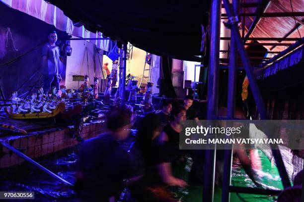 This picture taken on May 15, 2018 shows Vietnamese puppeteers controlling water puppets from behind a bamboo screen in a pool during a performance...