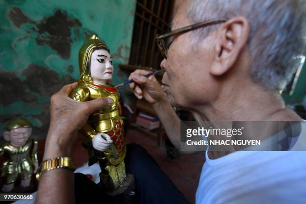 This picture taken on May 25, 2018 shows Vietnamese craftsman Pham Viet Duc putting finishing touches on a water puppet at a workshop in Thai Binh...