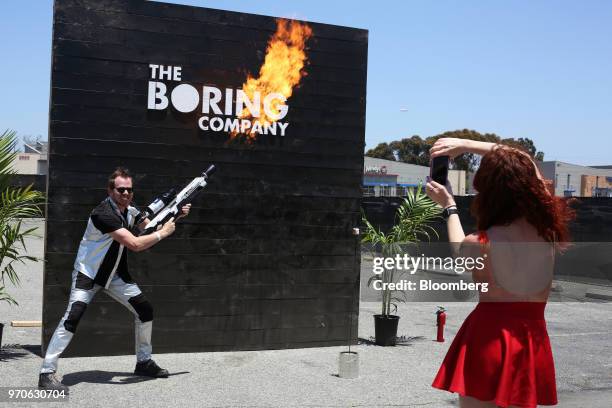 An attendee stands for a photograph while operating a Boring Co. Flamethrower during the company's Not-a-Flamethrower Party outside of the Space...