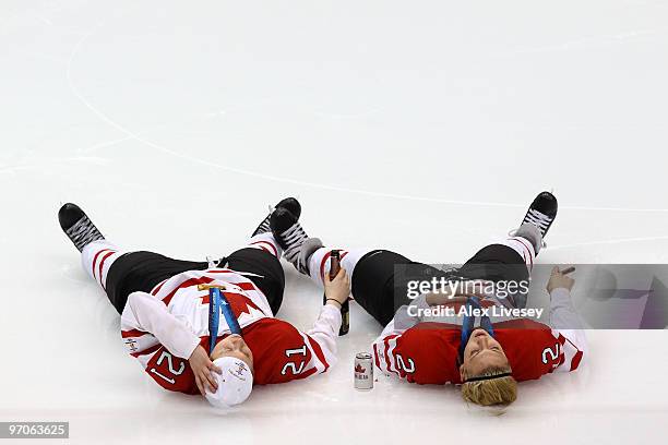 Haley Irwin and Meghan Agosta of Canada lie on the ice and celebrate winning the gold medal with a beer and a cigar following their team's 2-0...