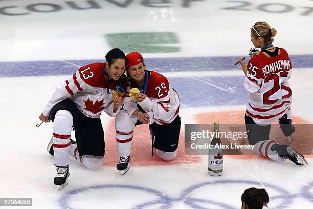 Caroline Ouellette, Marie-Philip Poulin and Tessa Bonhomme of Canada celebrate winning the gold medal with a beer and a cigar following their team's...