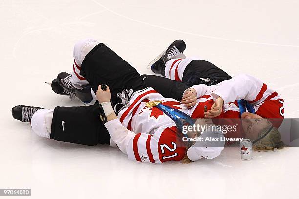 Haley Irwin and Meghan Agosta of Canada lie on the ice and celebrate winning the gold medal with bubbly, beer and a cigar following their team's 2-0...