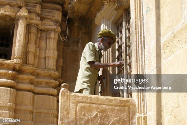 jain temple caretaker at the temple door, jaisalmer fort, north india - haveli stock pictures, royalty-free photos & images