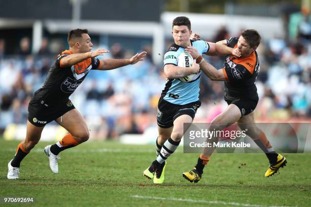 Luke Brooks and Chris Lawrence of the Tigers tackle Chad Townsend of the Sharks during the round 14 NRL match between the Cronulla Sharks and the...