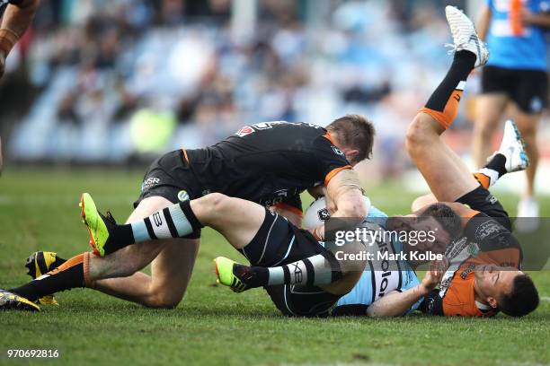 Chris Lawrence and Luke Brooks of the Tigers tackle Chad Townsend of the Sharks during the round 14 NRL match between the Cronulla Sharks and the...