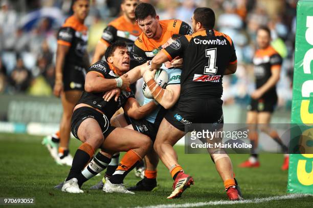 Elijah Taylor, Matt Eisenhuth and Tuimoala Lolohea of the Tigers attempt to tackle Paul Gallen of the Sharks before he scores try during the round 14...