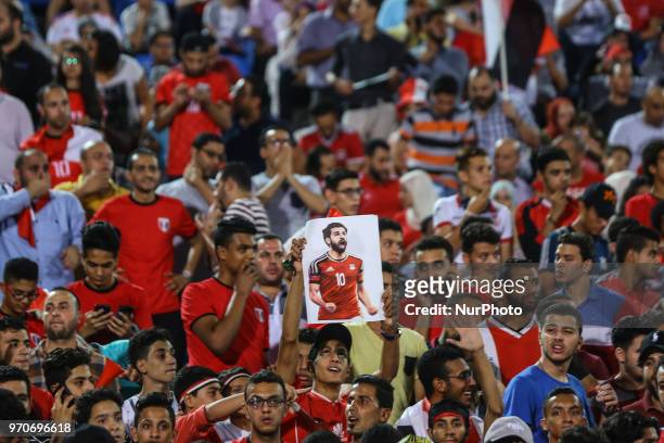 An Egyptian fan holds an image of national team footballer and Liverpool's Egyptian forward Mohamed Salah during the final practice training session...