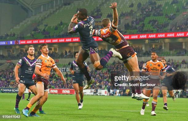 Suliasi Vunivalu of the Melbourne Storm beats Corey Oates of the Broncos to catch a high ball and then scores a try during the round 14 NRL match...