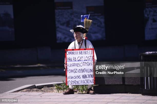 Lonely aged protester sitting with a sign denouncing Angela Merkel during a rally to protest the G7 summit in Quebec City, Canada on 9 June 2018....