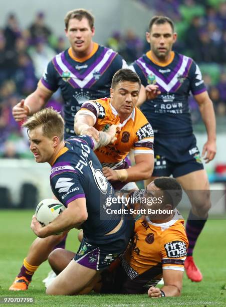 Cameron Munster of the Melbourne Storm is tackled during the round 14 NRL match between the Melbourne Storm and the Brisbane Broncos at AAMI Park on...