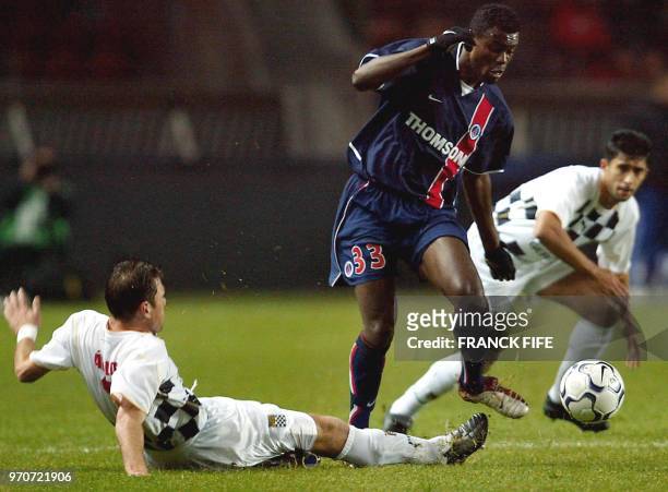 Le milieu de terrain du PSG Alex Nyarko est taclé par le défenseur du Boavista Porto Paulo César Turra , le 26 novembre 2002 au Parc des Princes à...