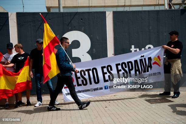 Men hold a banner reading "This is Spain" and Spanish flags during a demonstration called by far-right groups under the slogan "For the closure of...