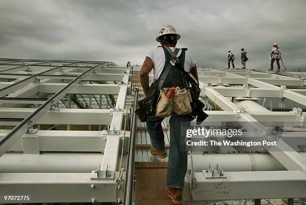 National Harbor, Oxon Hill, Maryland Natural Light workers, Gary Hartig, of Columbia Falls, Montana, foreground, walks along the roof as he works to...