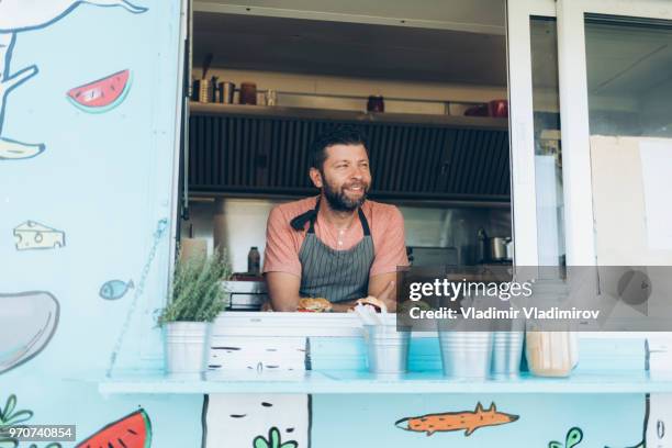 smiling man standing inside of a food van - food truck festival stock pictures, royalty-free photos & images