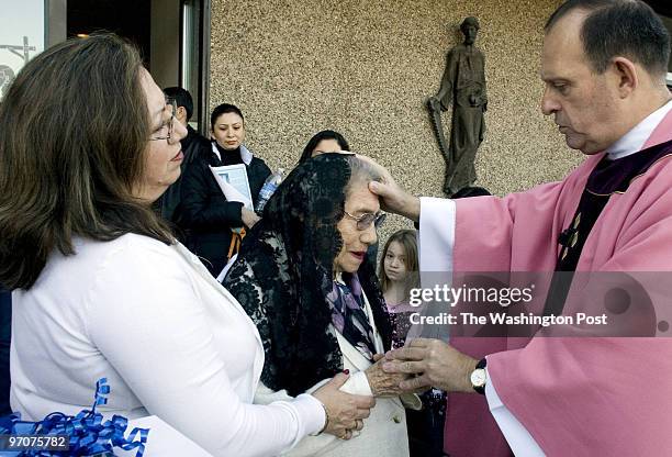 Kevin Clark/TWP Neg #: 198591 Herndon, VA Father Jose Hoyos, right, prayers with Maria Ayala as her daughter, Ana Ayala, left, looks on Sunday...