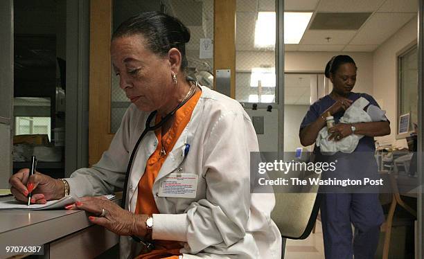 Washington, DC, SE Chris Groover, RN, catches up on paperwork as Jackie Johnson, RN attends to the needs of a newborn in the neonatal unit during a...