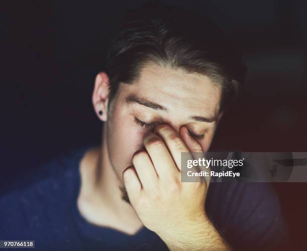 exhausted or depressed young man rubbing his eyes - man rubbing eyes stock pictures, royalty-free photos & images