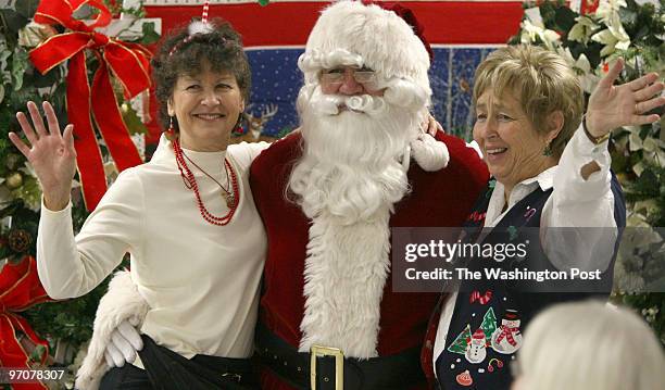 Elda Banks, left, and Katherine Davis, pose for photos with Carl Johnson, playing the role of Santa Claus at a holiday pancake breakfast community...