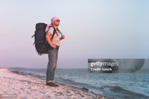 a man with a backpack side view the sea - sand spit stock pictures, royalty-free photos & images