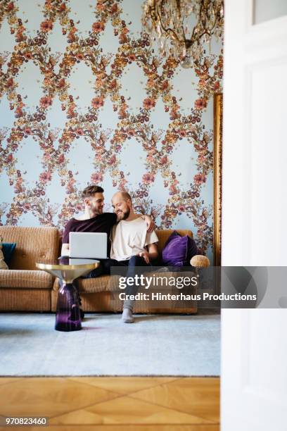 gay couple relaxing on couch together - hinterhaus stockfoto's en -beelden