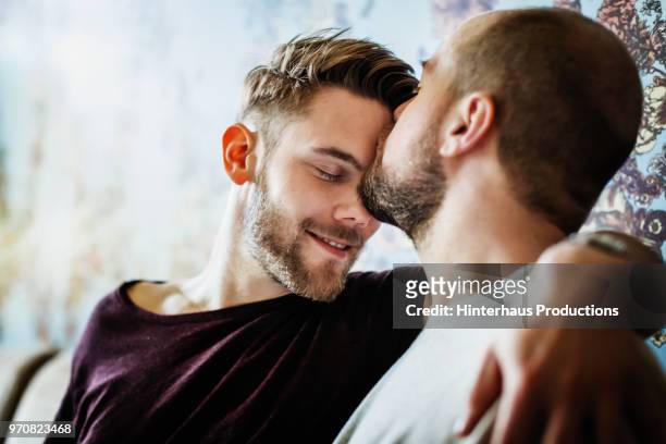 gay man kissing his partner on the head - romantic foto e immagini stock